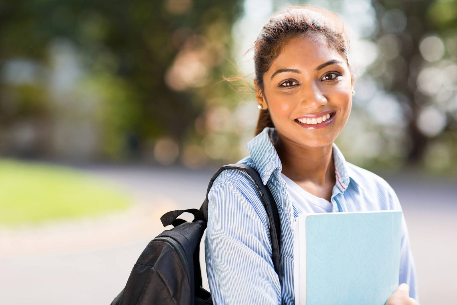 smiling female holding book with backpack
