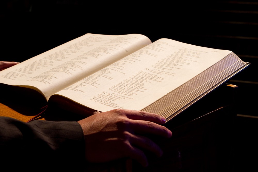 Minister reading from a large Bible at a pulpit