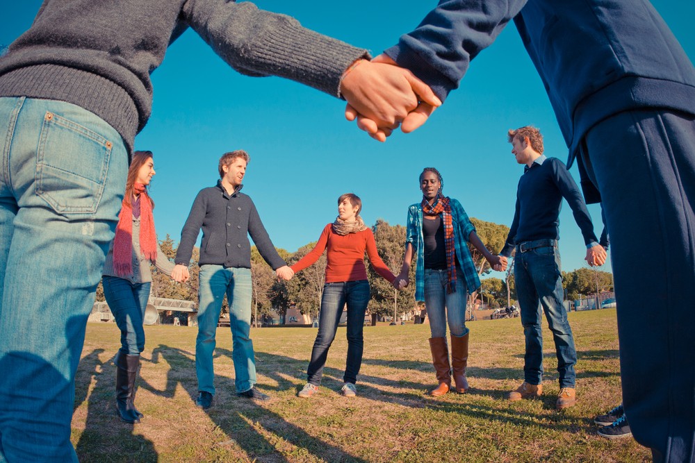 Multi-ethnic group of young people holding hands in a circle