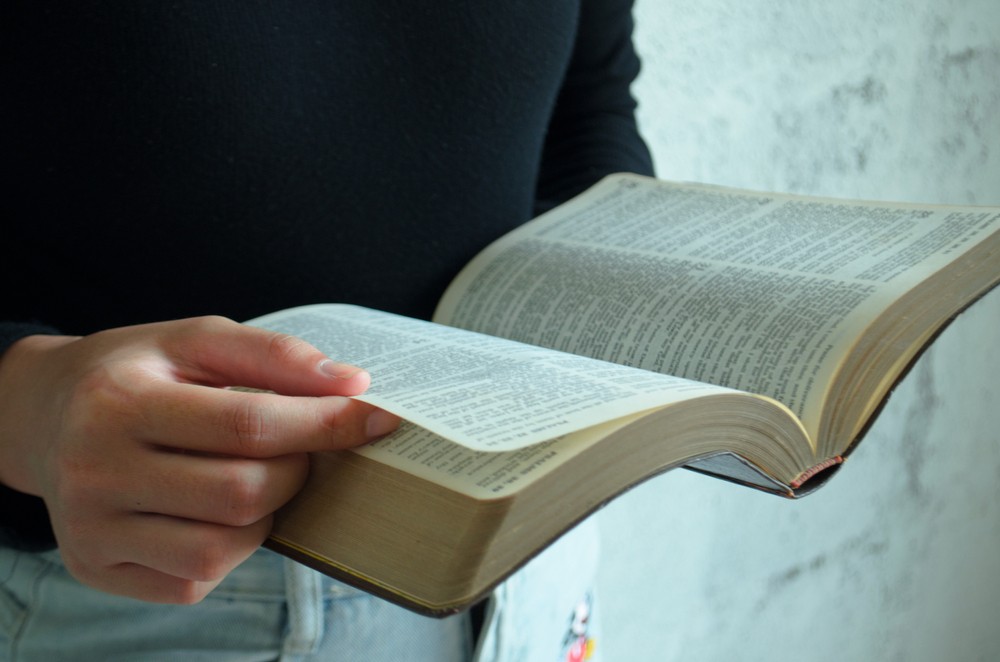 Man standing up reading open the Bible