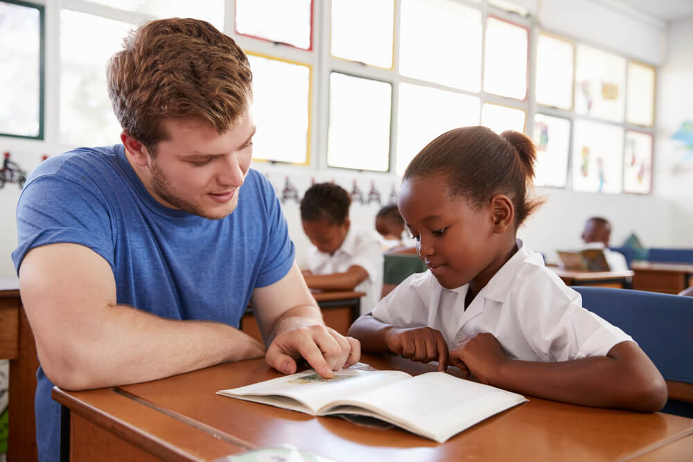 college student tutoring African school child in service learning program