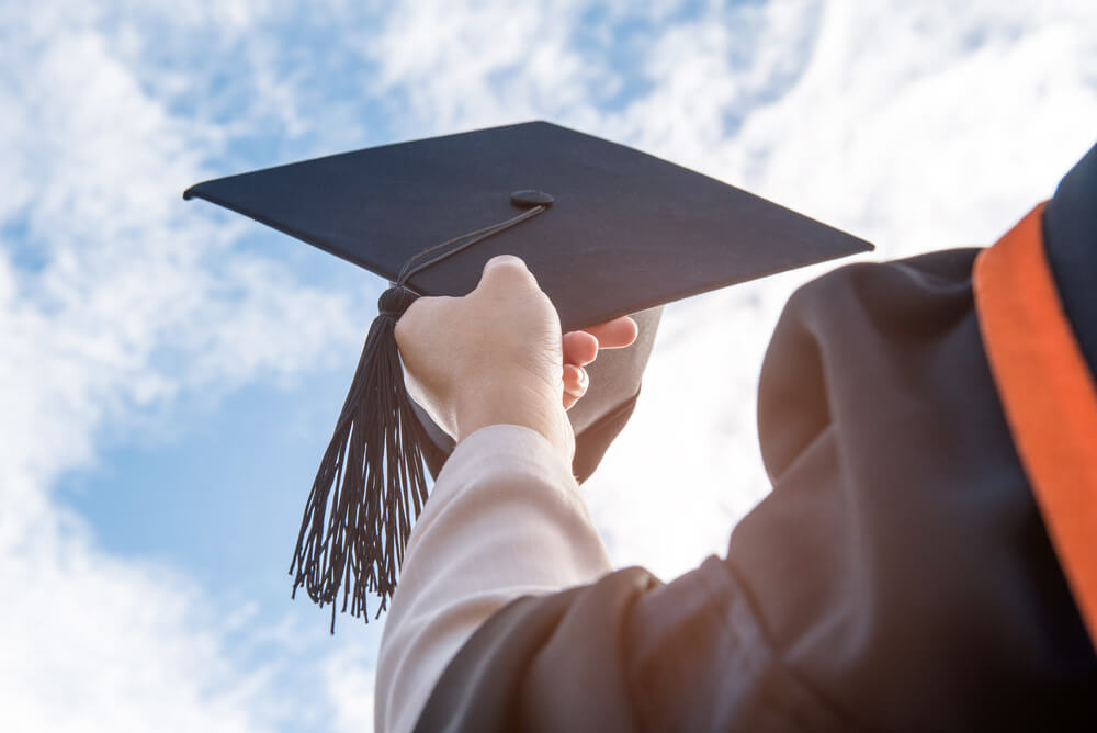 college graduate holding graduation cap